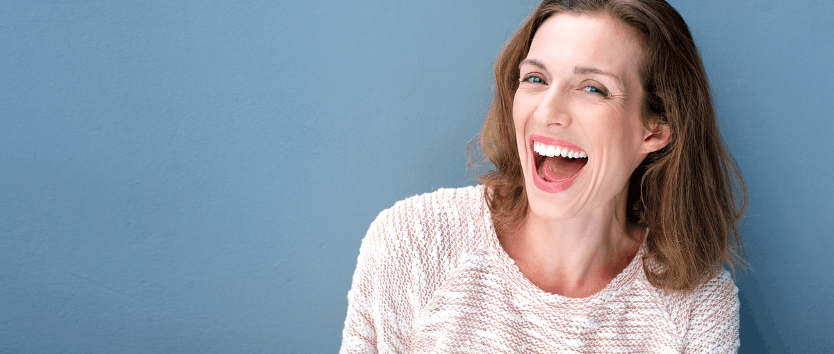 Mujer adulta sonriendo felizmente tras su tratamiento de ortodoncia invisible Invisalign